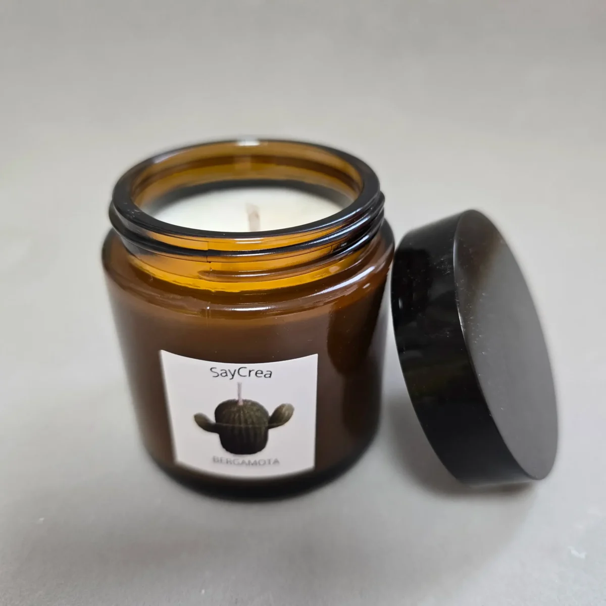 Vela aromática en recipiente color ámbar de de cera de soja con mecha de algodón encerada.